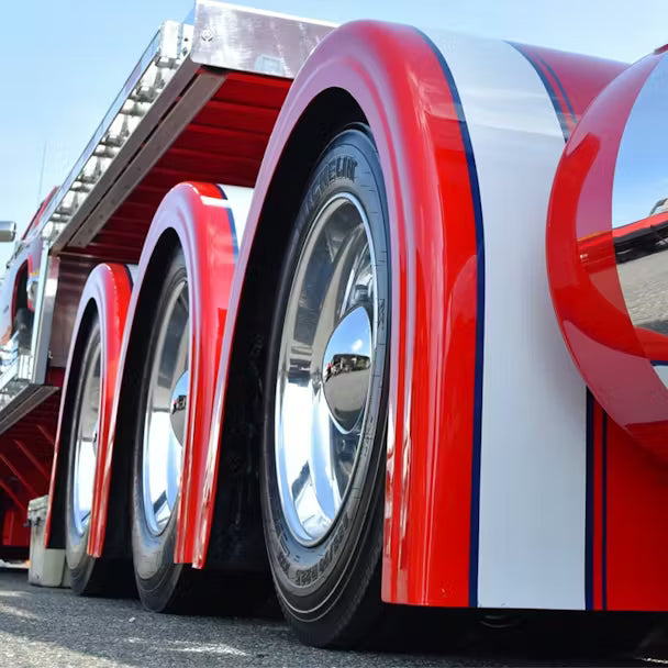 Close-up of a large truck with red and white striped wheels on a clear day.