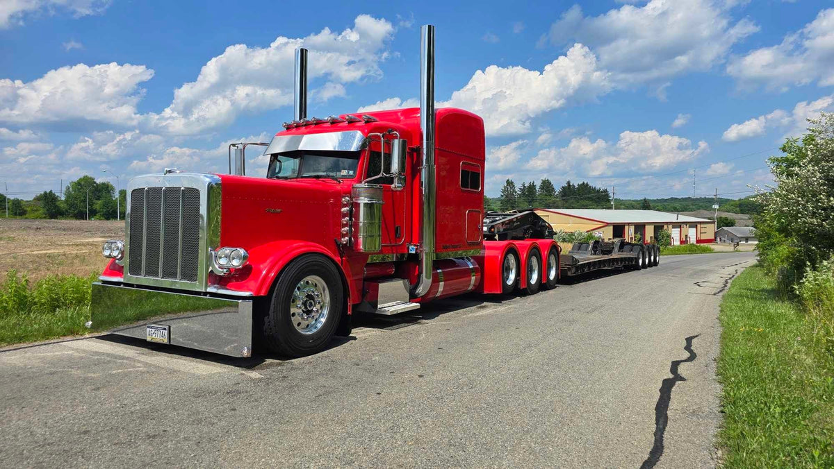 Red Peterbilt pulling a lowboy trailer, fitted with Bad Ass custom fiberglass fenders